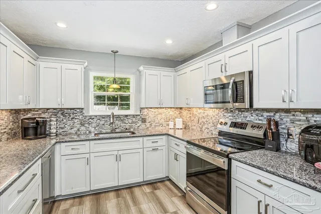 a kitchen with stainless steel appliances granite countertop a sink stove and microwave