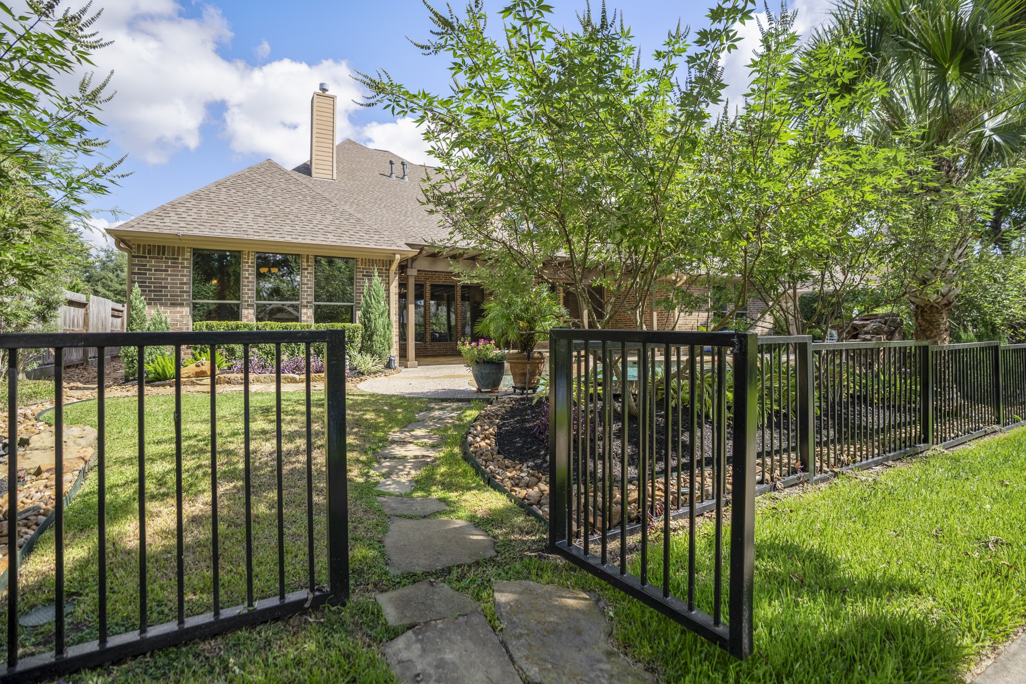 2407 Hendricks Lakes Drive Spring, TX 77388 - Photo 40 of 50 Stepping through the backyard gate, the home’s water-front lifestyle continues onto the neighborhood trails just beyond the fence. The black wrought-iron fencing keeps the backyard visually connected to the lakeside setting, so the pool, covered pergola, and outdoor living spaces feel tied to the paths, water, and greenery that make Lakes of Cypress Forest so memorable.