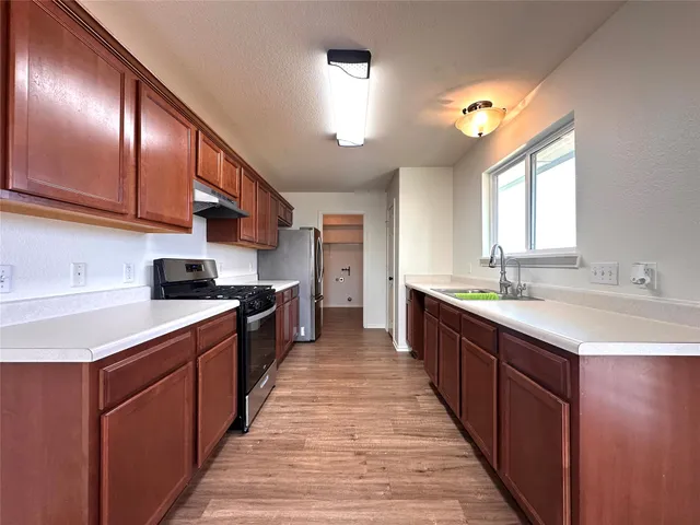 a large kitchen with stainless steel appliances wooden cabinets a sink and a stove