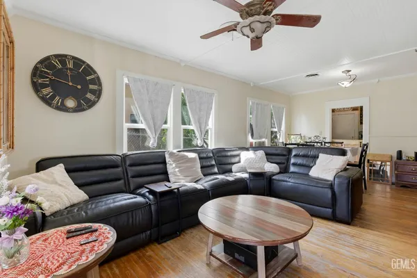 a living room with furniture a ceiling fan and a large window