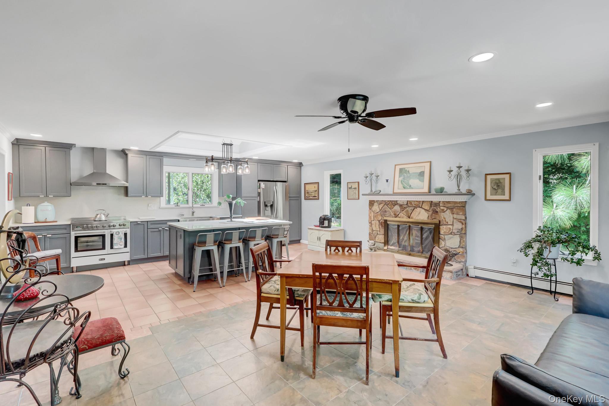 100 Elwood Road Northport, NY 11768 - Photo 10 of 39 Open-concept great room featuring a chef's kitchen, stone fireplace, and wood-finish flooring