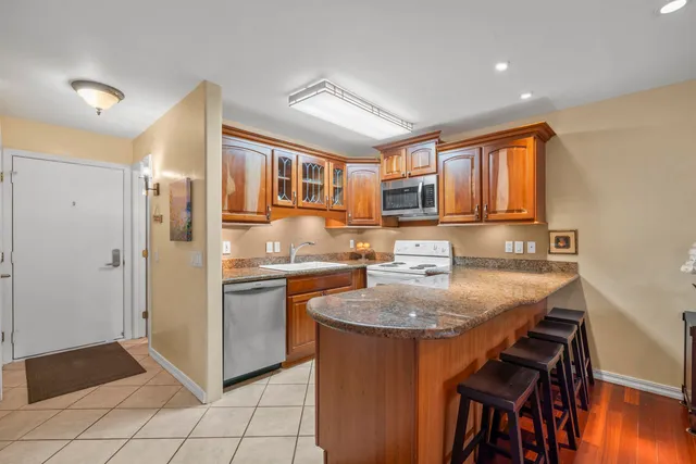 a kitchen with stainless steel appliances granite countertop a refrigerator a sink a stove a microwave and island