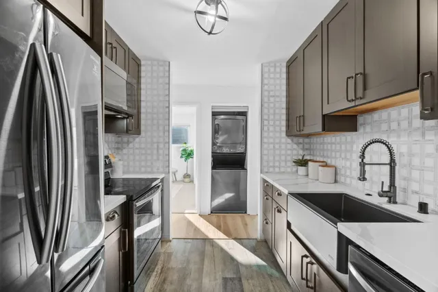 a kitchen with stainless steel appliances a sink a stove a refrigerator and cabinets
