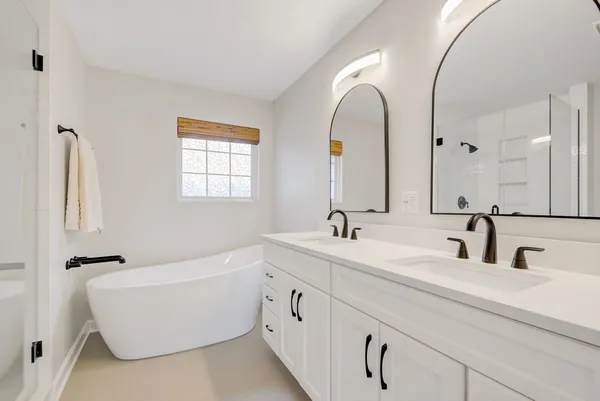 a bathroom with a white tub a sink and mirror