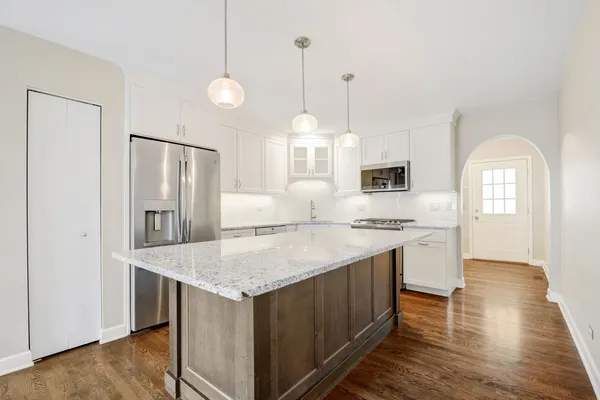 a kitchen with stainless steel appliances granite countertop a sink a stove a refrigerator and island with wooden floor