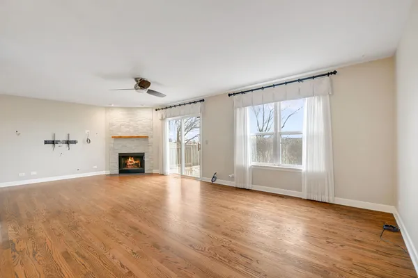 an empty room with windows fireplace and wooden floor