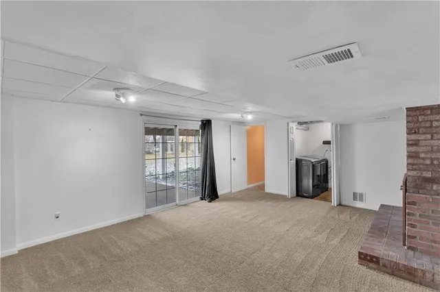 a view of an empty room with a fireplace and a window