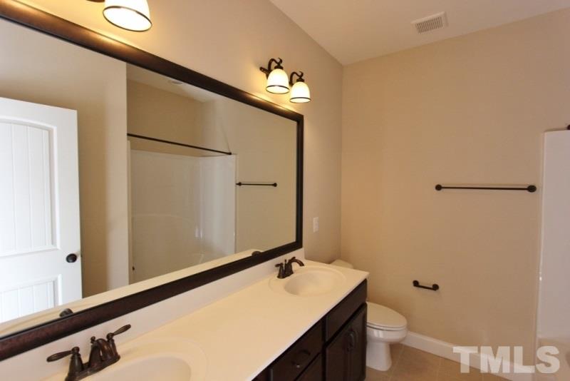 201 Virginia Water Drive Rolesville, NC 27571 - Photo 16 of 25 a bathroom with a sink and mirror with toilet