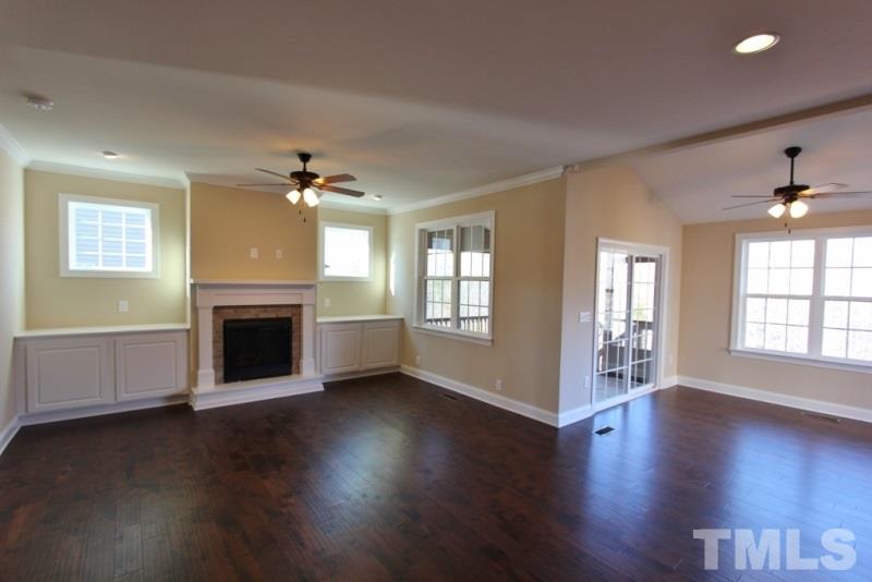 201 Virginia Water Drive Rolesville, NC 27571 - Photo 6 of 25 an empty room with wooden floor fireplace and windows