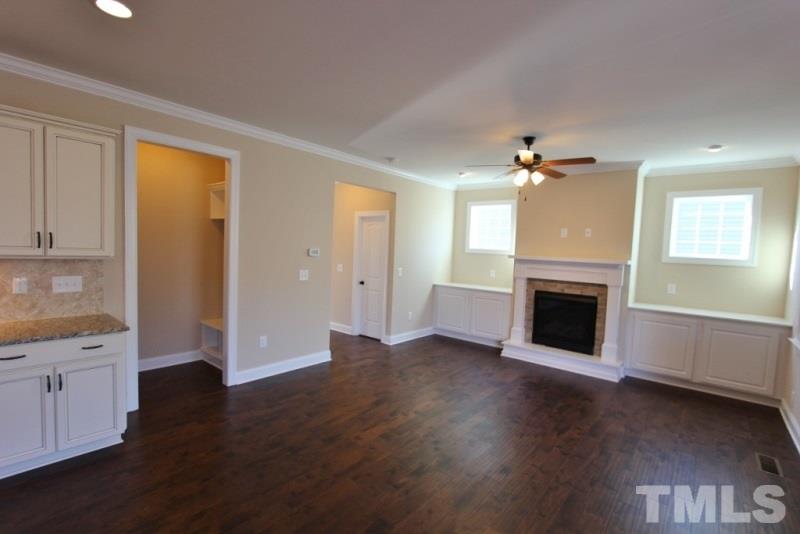 201 Virginia Water Drive Rolesville, NC 27571 - Photo 7 of 25 an empty room with wooden floor fireplace and windows