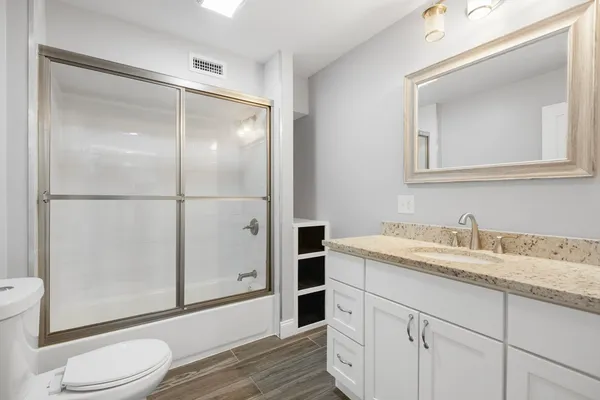a bathroom with a granite countertop sink toilet and shower