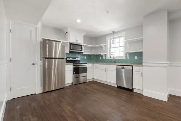a kitchen with a refrigerator a sink and wooden floor