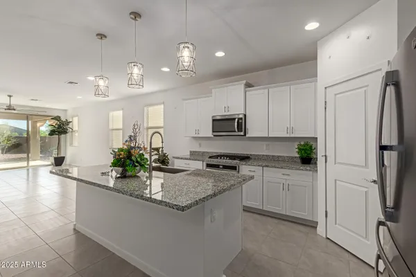a kitchen with stainless steel appliances granite countertop a sink a stove a refrigerator and white cabinets
