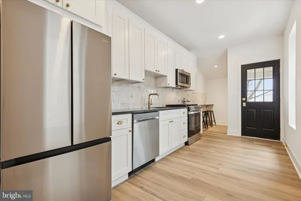 a kitchen with granite countertop a refrigerator stove top oven and sink