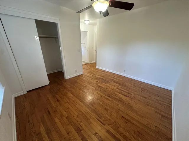 an empty room with wooden floor cabinet and windows