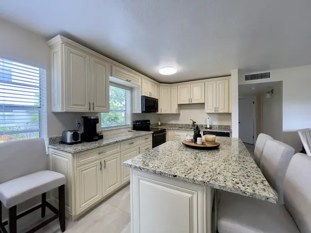 a kitchen with granite countertop kitchen island sink stove top oven and microwave