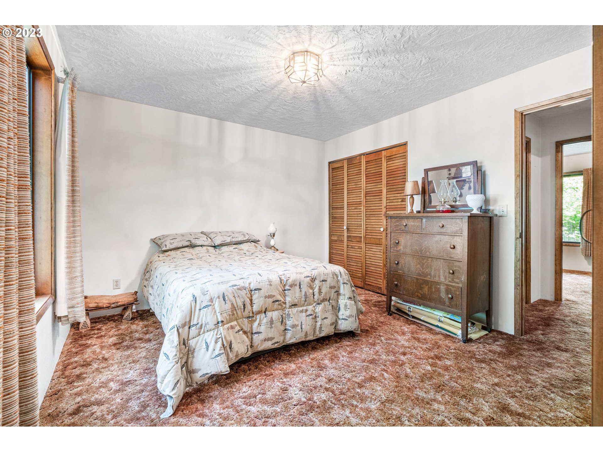 65582 East Timberline Drive Rhododendron, OR 97049 - Photo 17 of 48 a spacious bedroom with a bed and a chandelier