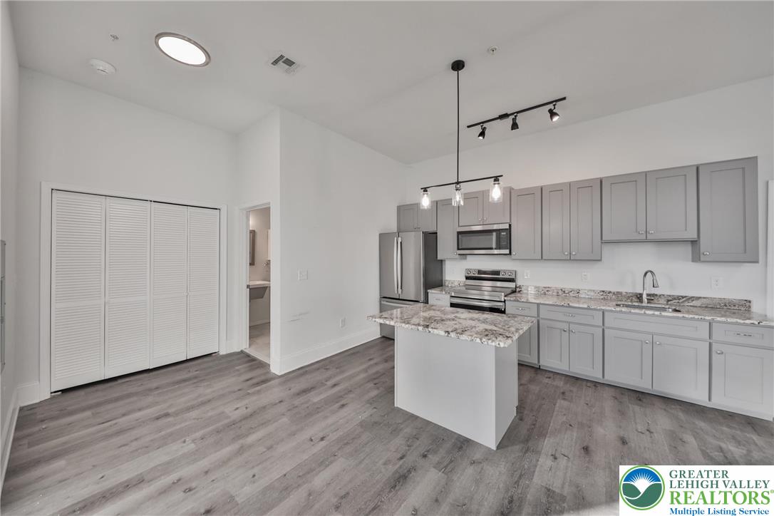 10 West Goepp Street, Unit 207 Bethlehem, PA 18018 - Photo 9 of 24 a kitchen with kitchen island white cabinets and wooden floor