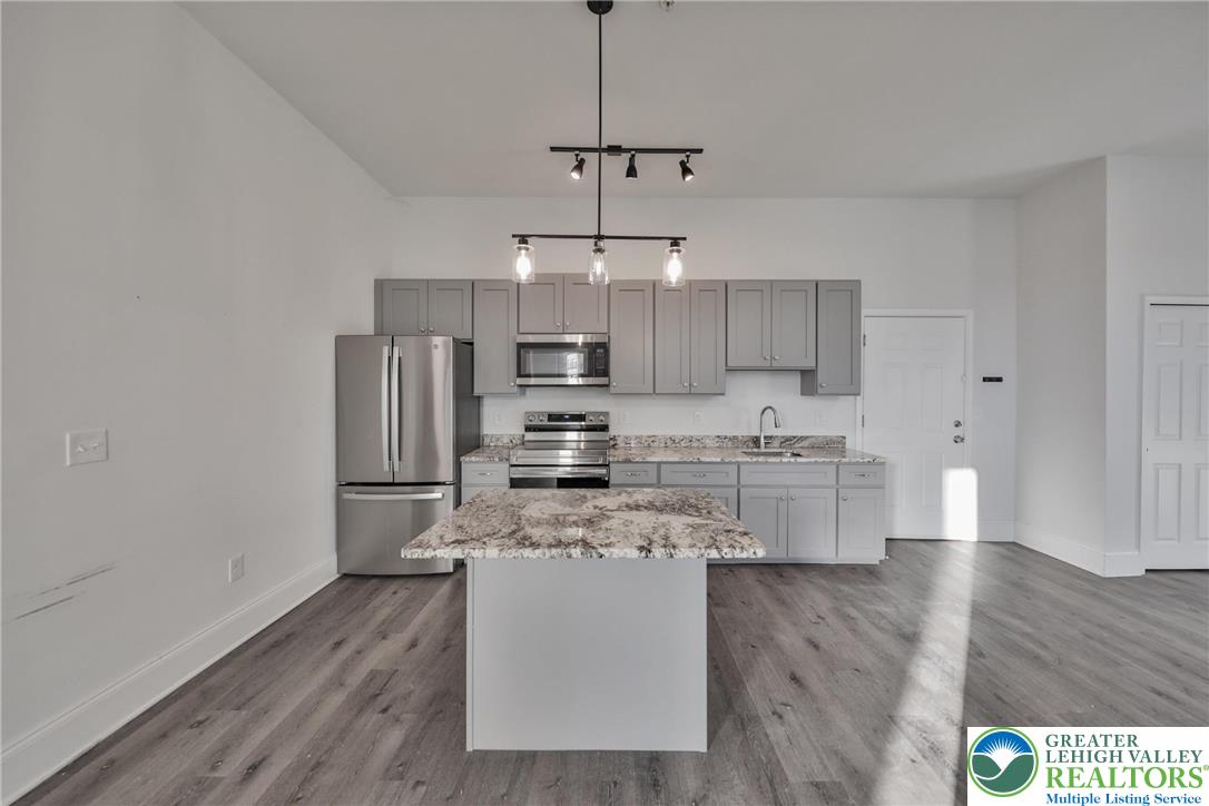 10 West Goepp Street, Unit 207 Bethlehem, PA 18018 - Photo 10 of 24 a kitchen with stainless steel appliances a refrigerator a stove a sink dishwasher and white cabinets with wooden floor