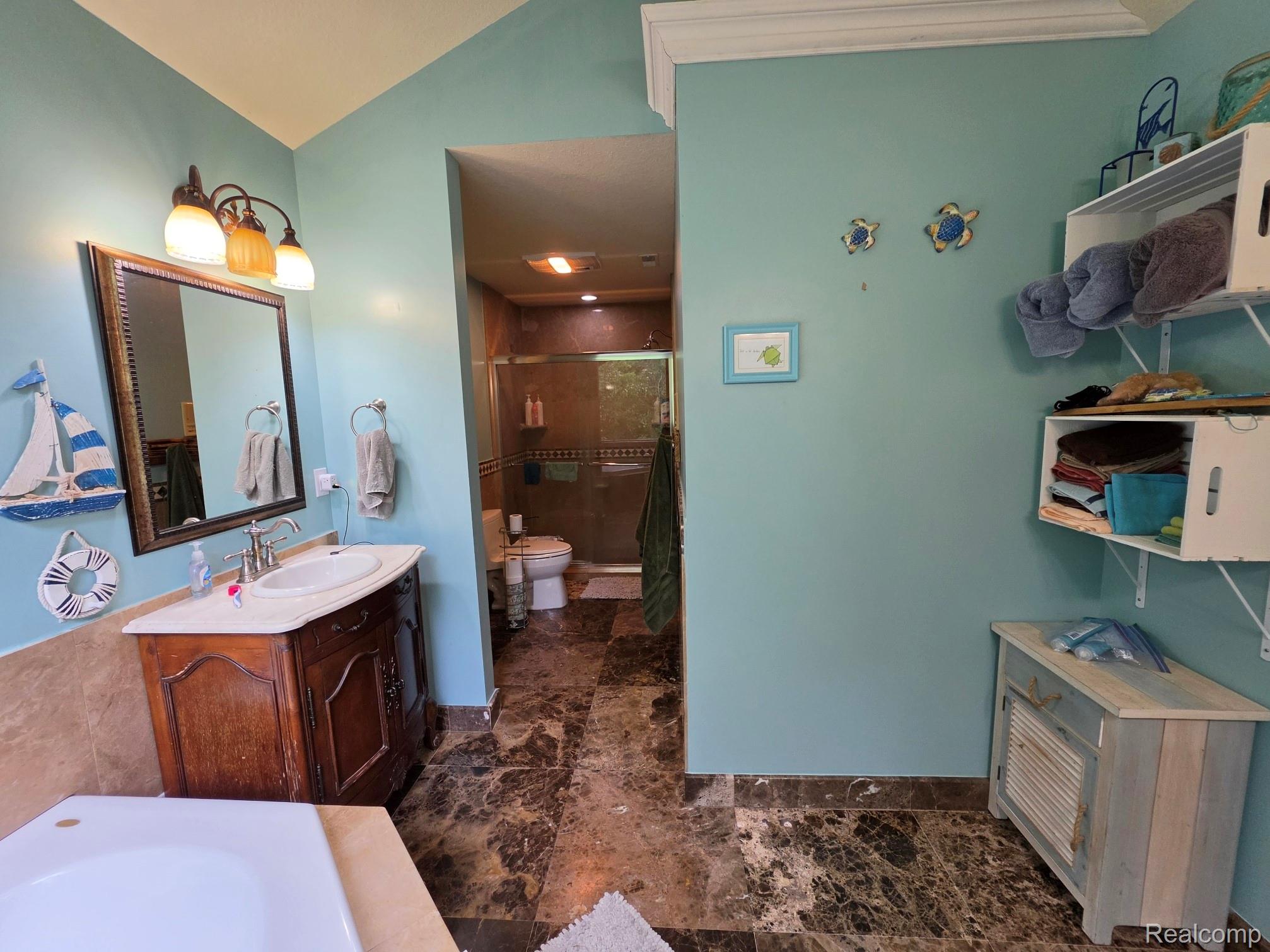 5150 West Carpenter Road Flint, MI 48504 - Photo 23 of 33 Bathroom featuring a single vanity with an oval sink, a framed mirror, and warm-toned wall lighting