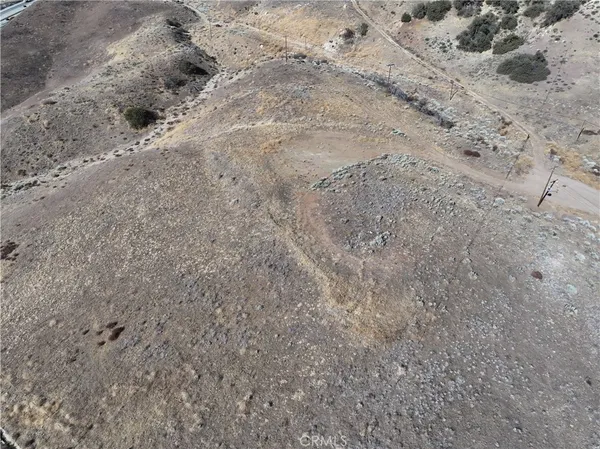 a view of a dry field with trees in the background