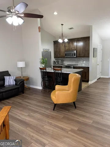 a living room with furniture kitchen view and a wooden floor