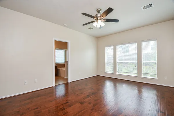 an empty room with wooden floor and windows