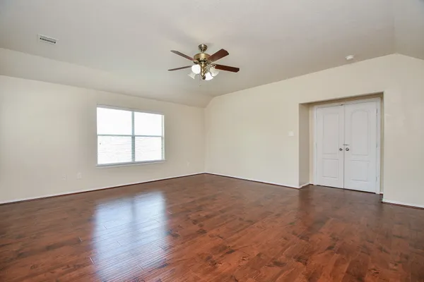 an empty room with wooden floor fan and windows