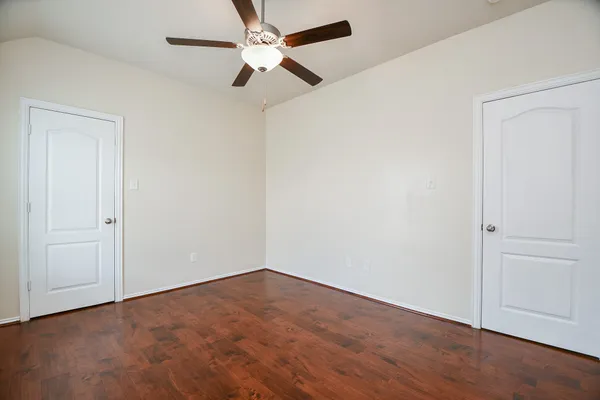 an empty room with wooden floor ceiling fan and window