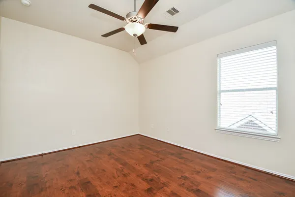 an empty room with a window and a fan