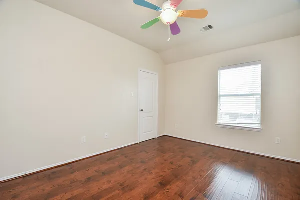 an empty room with wooden floor fan and windows