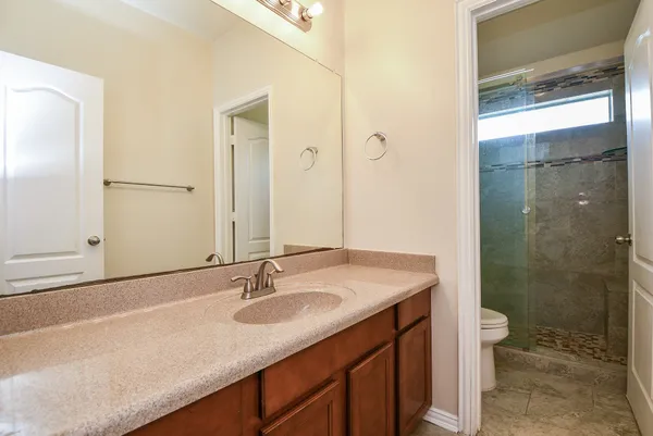 a bathroom with a granite countertop sink a toilet a shower and a mirror