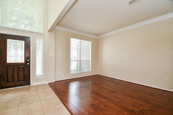 an empty room with wooden floor and windows