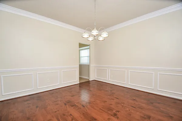 an empty room with wooden floor chandelier fan and windows