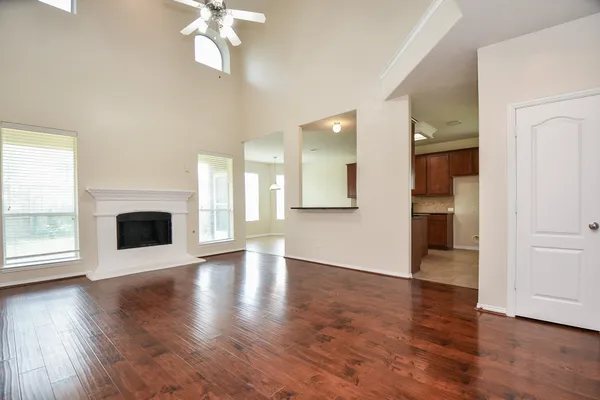 an empty room with wooden floor and a kitchen