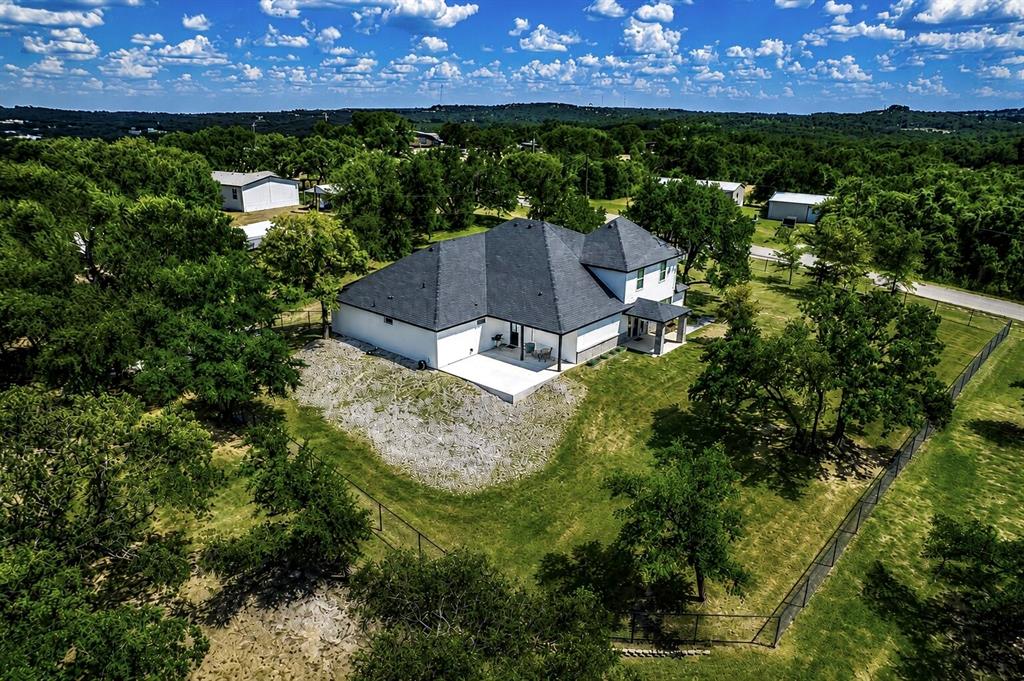 117 Rock Salt Drive Springtown, TX 76082 - Photo 6 of 38 Newly constructed residence featuring a dark shingle roof, white siding, and a covered back patio