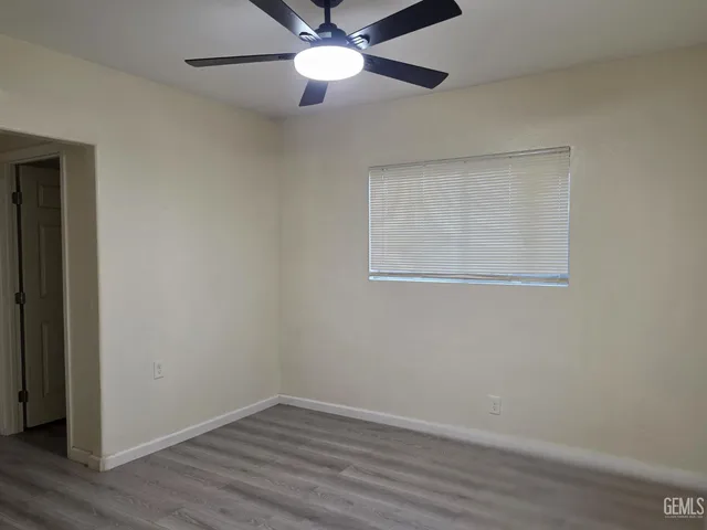 an empty room with wooden floor closet and fan