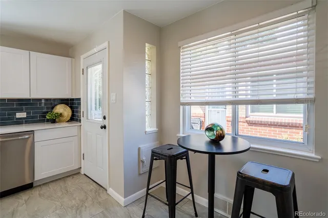 a kitchen with stainless steel appliances a sink a window and table chair