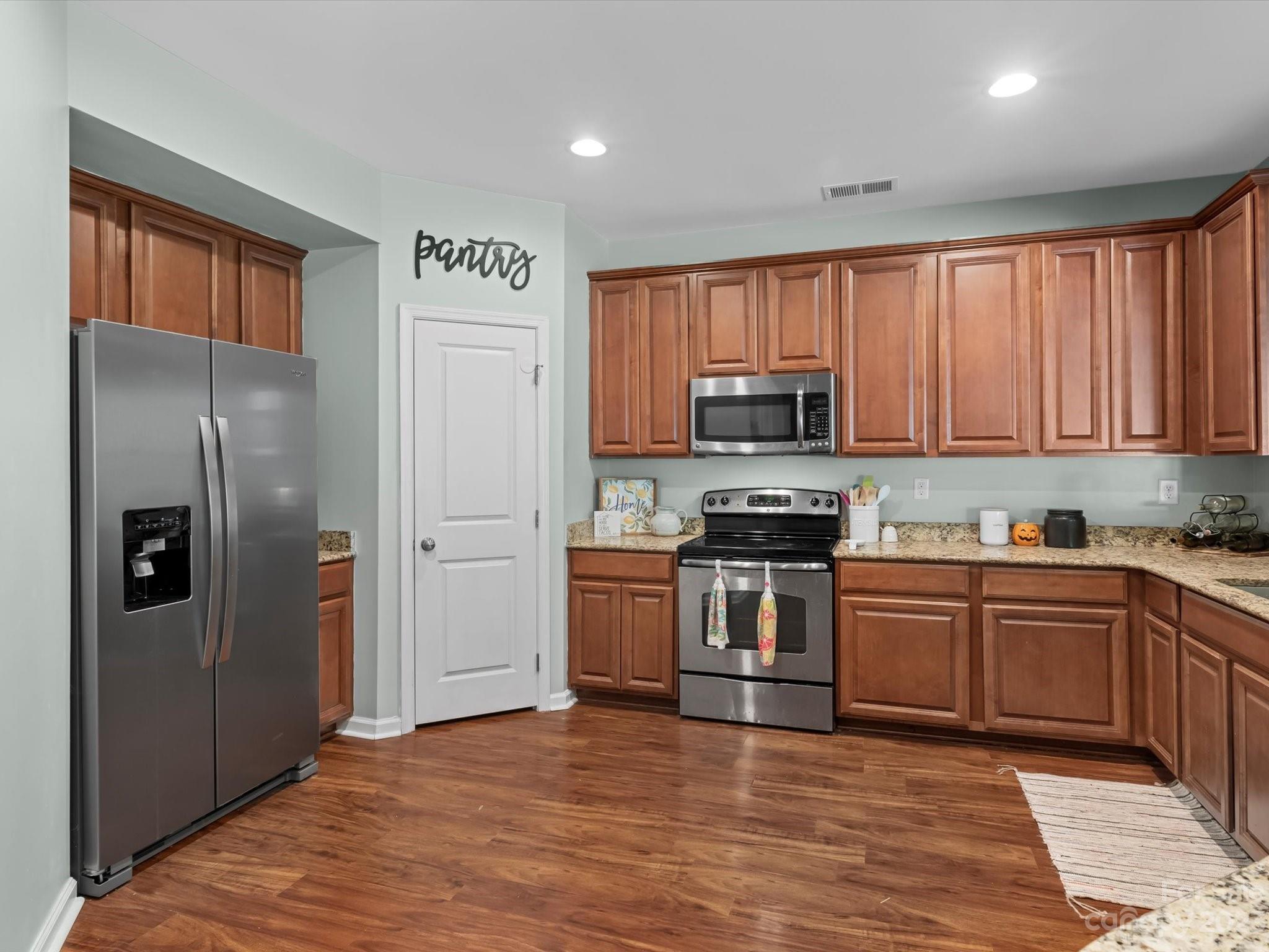 7634 West Berkeley Road Denver, NC 28037 - Photo 8 of 25 a kitchen with granite countertop stainless steel appliances and wooden cabinets