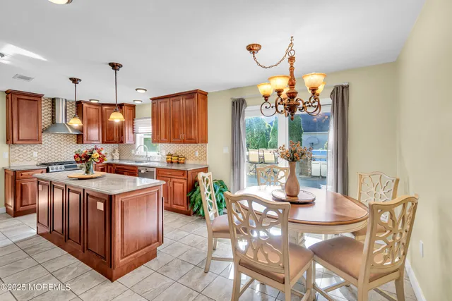 a kitchen with stainless steel appliances granite countertop a stove top oven a dining table and chairs with wooden floor