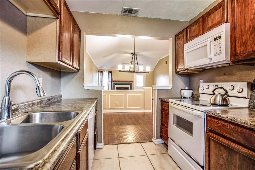 6817 Haltom Road Fort Worth, TX 76137 - Photo 20 of 25 Kitchen featuring a double stainless steel sink with a gooseneck faucet, white electric range, white built-in microwave, wood-finish cabinetry, and tiled flooring