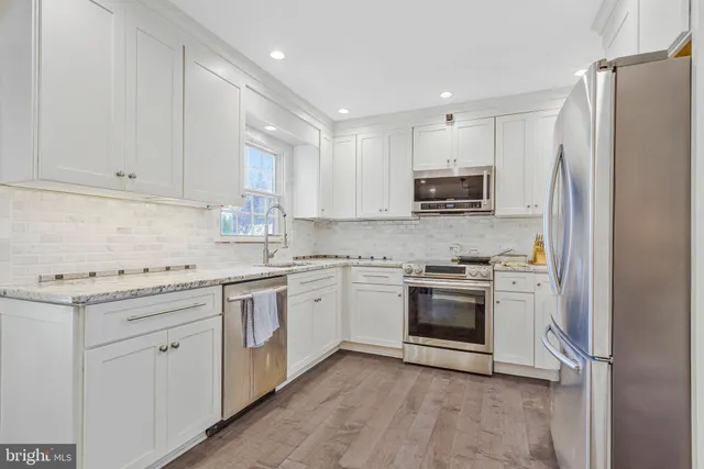 a kitchen with granite countertop white cabinets and stainless steel appliances