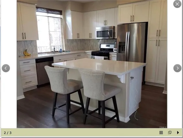 a kitchen with stainless steel appliances a dining table chairs refrigerator and sink
