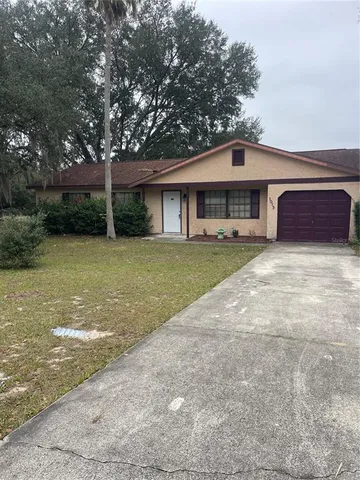 a view of a house with a yard and large tree