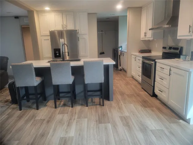 a kitchen with stainless steel appliances a dining table chairs refrigerator and sink