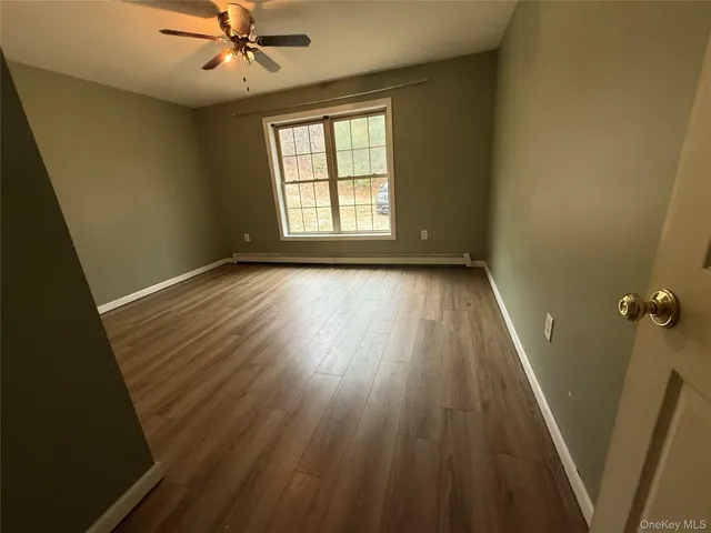 an empty room with wooden floor fan and windows