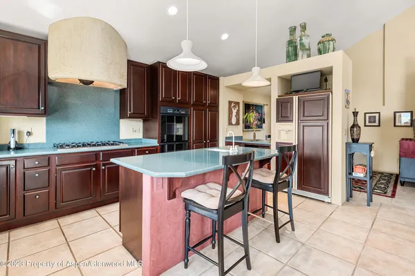 a kitchen with stainless steel appliances granite countertop a stove a sink a refrigerator and chairs