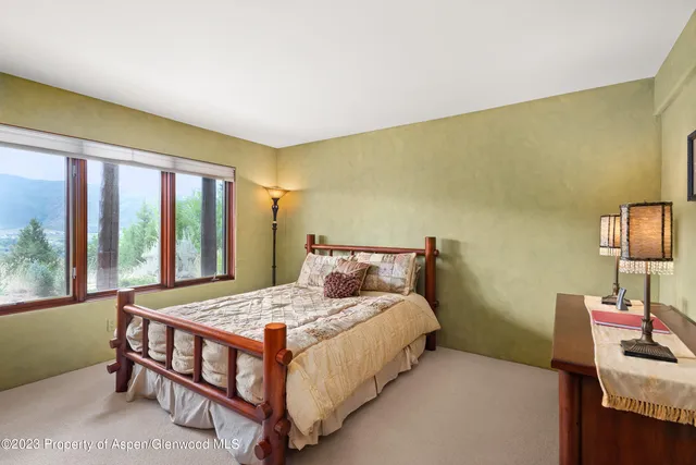 a bedroom with a bed table and a large window