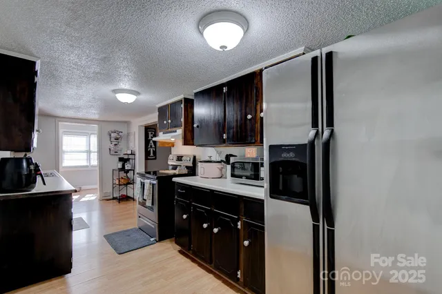 a kitchen with stainless steel appliances granite countertop a refrigerator a sink dishwasher and a stove with wooden floor