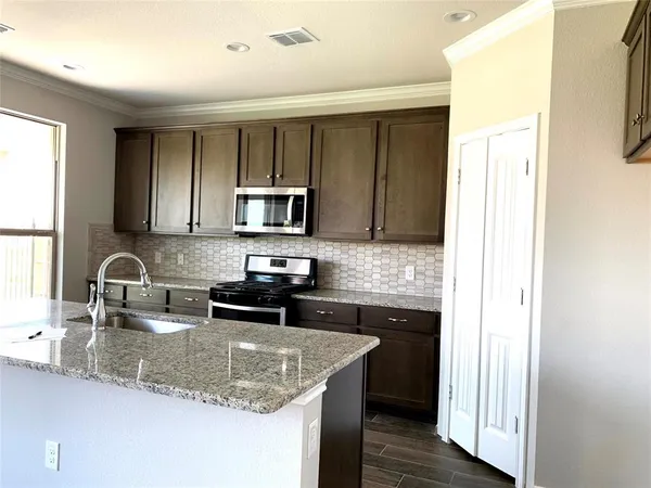a kitchen with kitchen island granite countertop a sink stove and refrigerator
